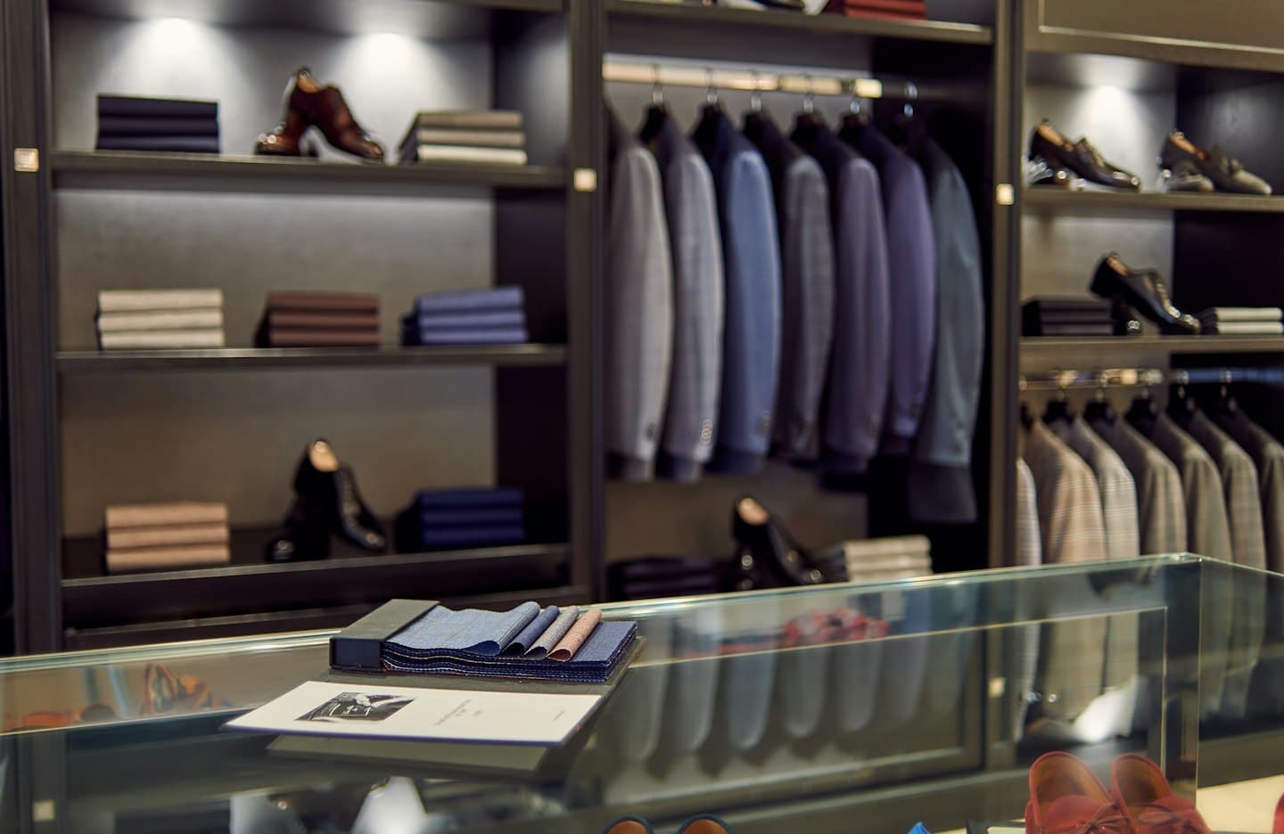 Men's clothing boutique with suit jackets and leather shoes.